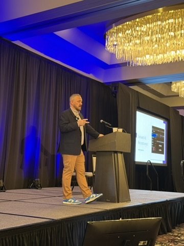Casey Nelson speaking on stage at an insurance industry conference